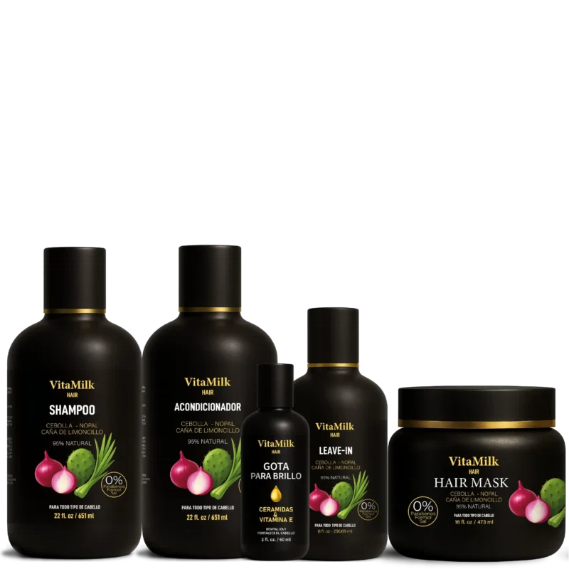Cinco productos capilares de la línea VitaMilk Hair con extractos de cebolla, nopal y caña de limón, presentados en envases negros elegantes con detalles dorados. Incluye champú, acondicionador, mascarilla, gota para brillo y crema para peinar.